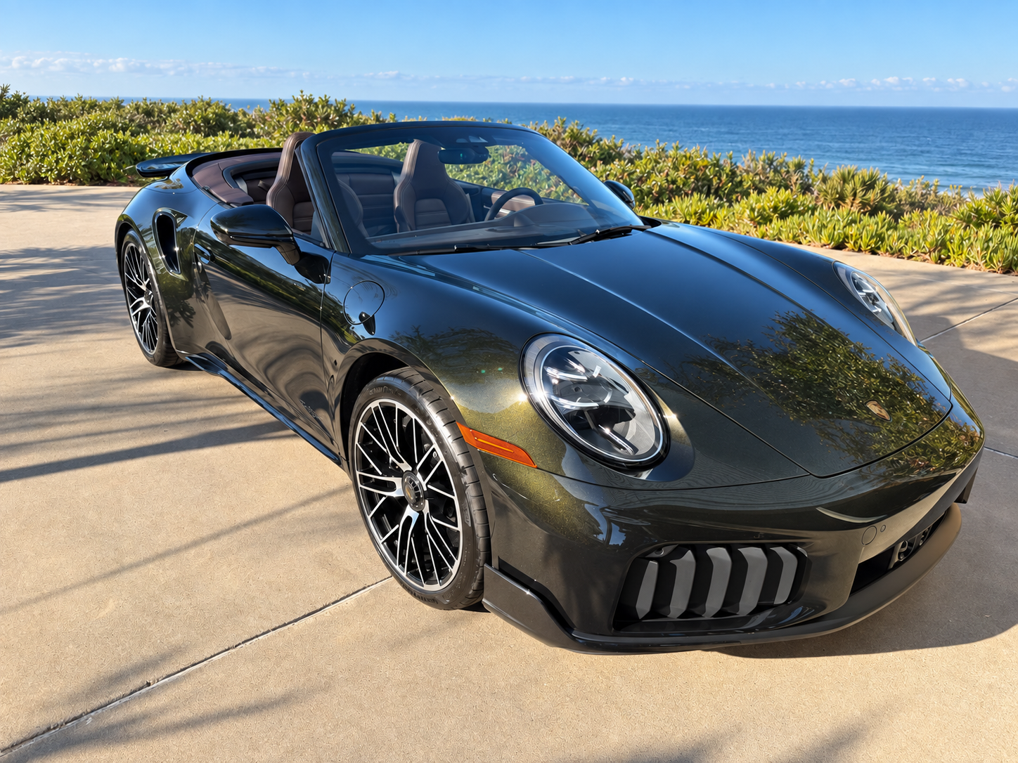 Top-down front three-quarter view showing the Paint to Sample Dark Olive Green Metallic finish in direct sunlight